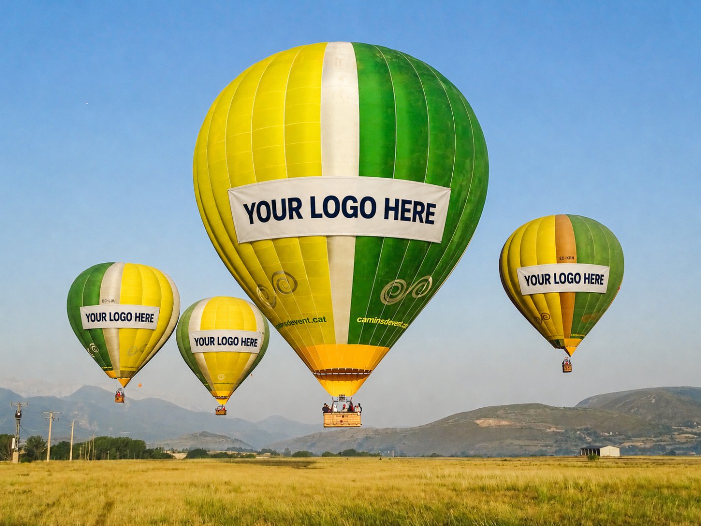 Quatre montgolfières de Camins de Vent avec des banderoles publicitaires indiquant Your Logo Here