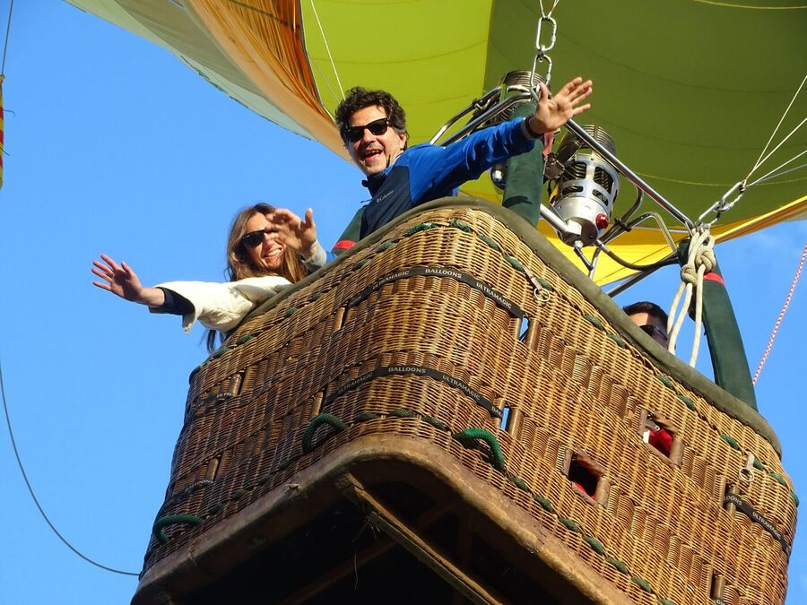 Pareja saludando desde la cesta de un globo